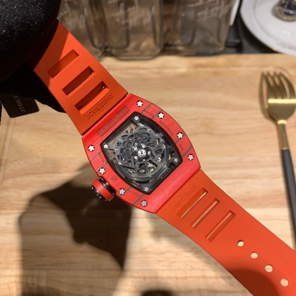 Orange watch strap underside with ridged panels and strap holes, gloved view