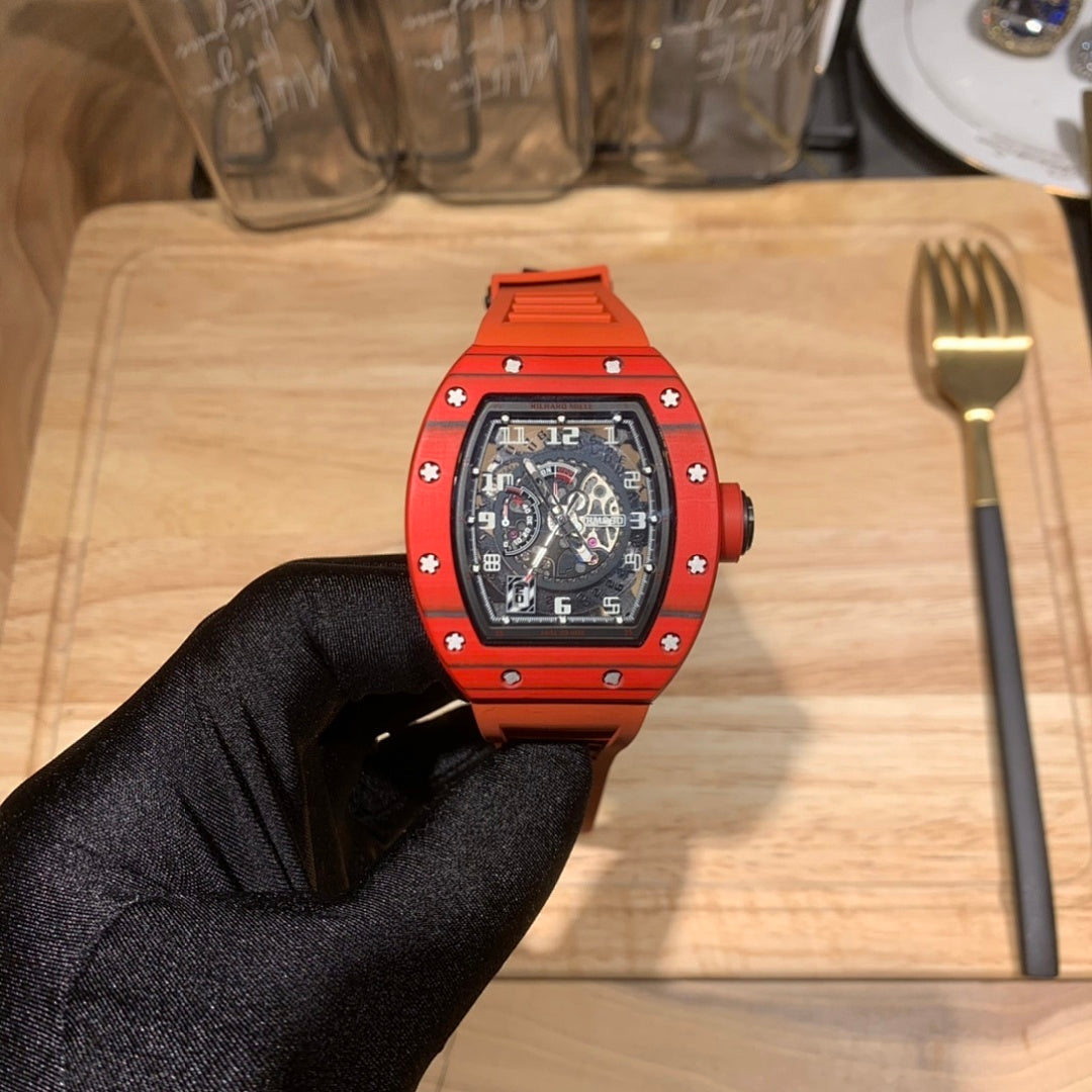 Orange watch with black dial, full front view held in black-gloved hand