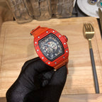 Orange sports watch with black dial, side hardware visible, gloved hand holding
