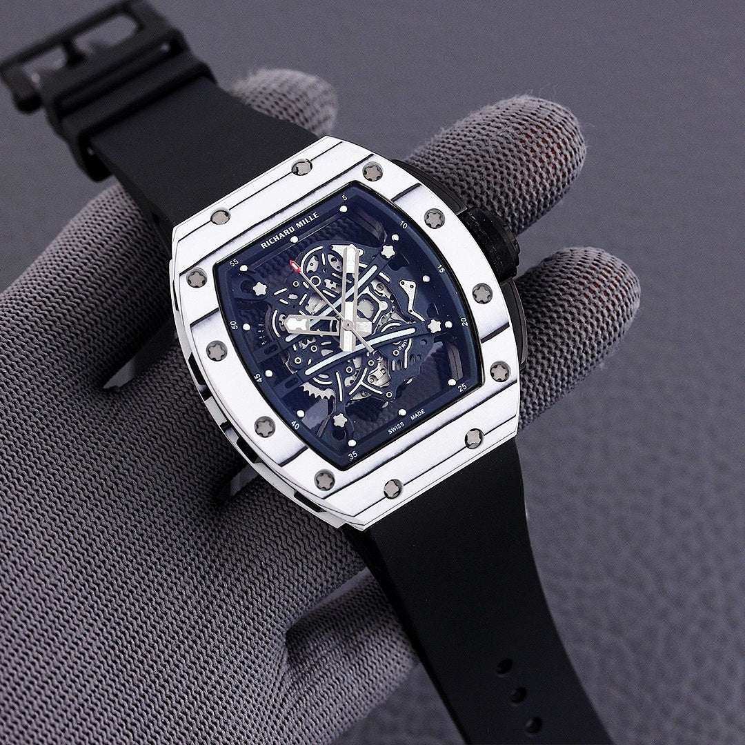 Richard Mille watch with white-toned case, blue skeleton dial, and black rubber strap.
