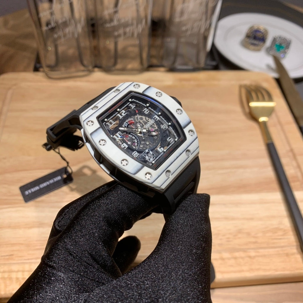 Richard Mille watch with black dial, silver case, and black rubber strap with buckle