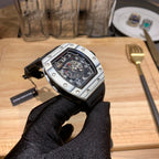 Richard Mille watch with black dial, silver case, and black rubber strap with buckle