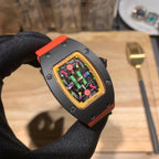 Richard Mille watch with black case and gold bezel, orange strap, colorful visible movement dial