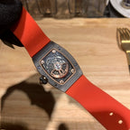 Watch with orange strap, see-through case back showing mechanical movement
