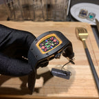Black Richard Mille watch on black strap with multicolor dial, side profile