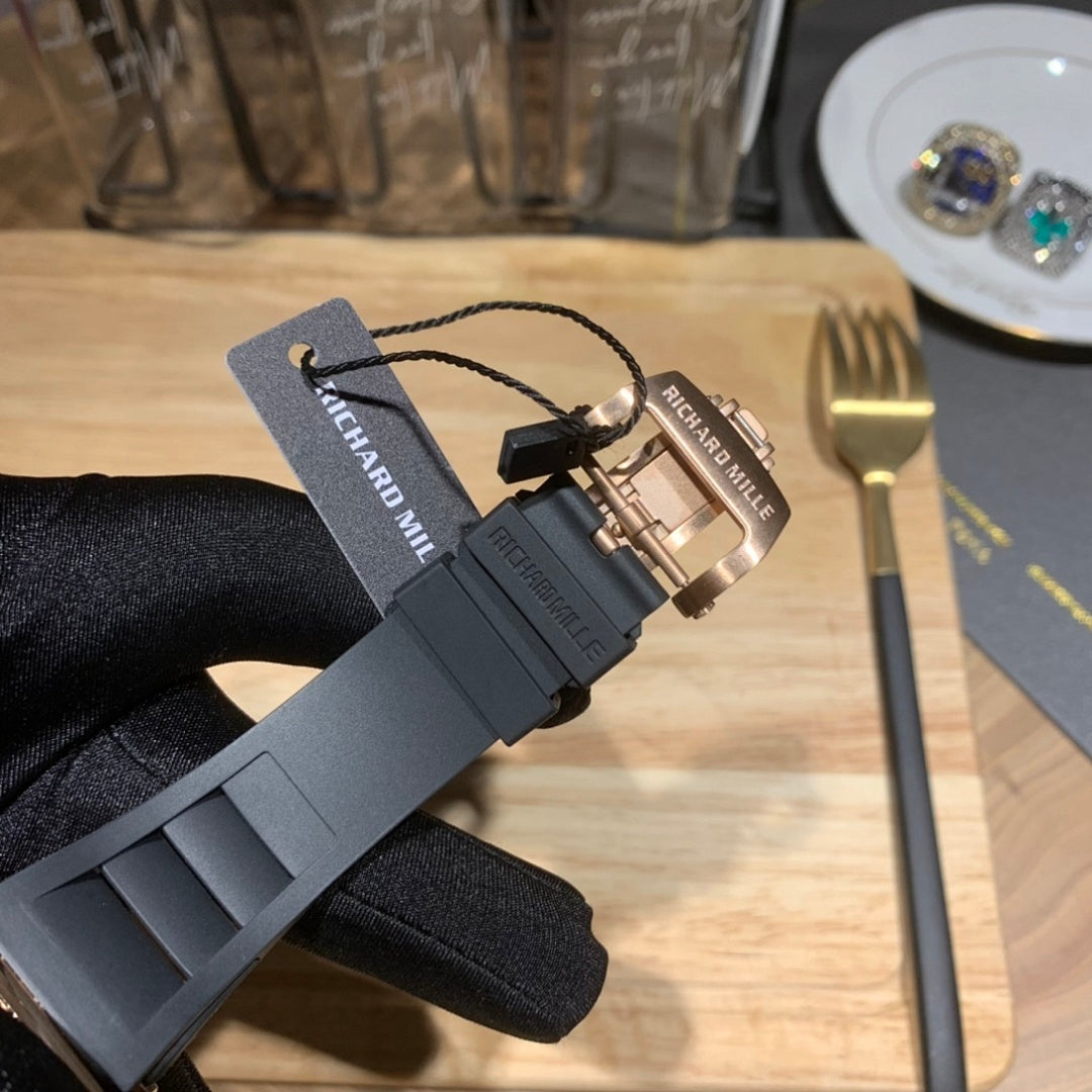 Black rubber watch strap with buckle and Richard Mille tag on gloved hand