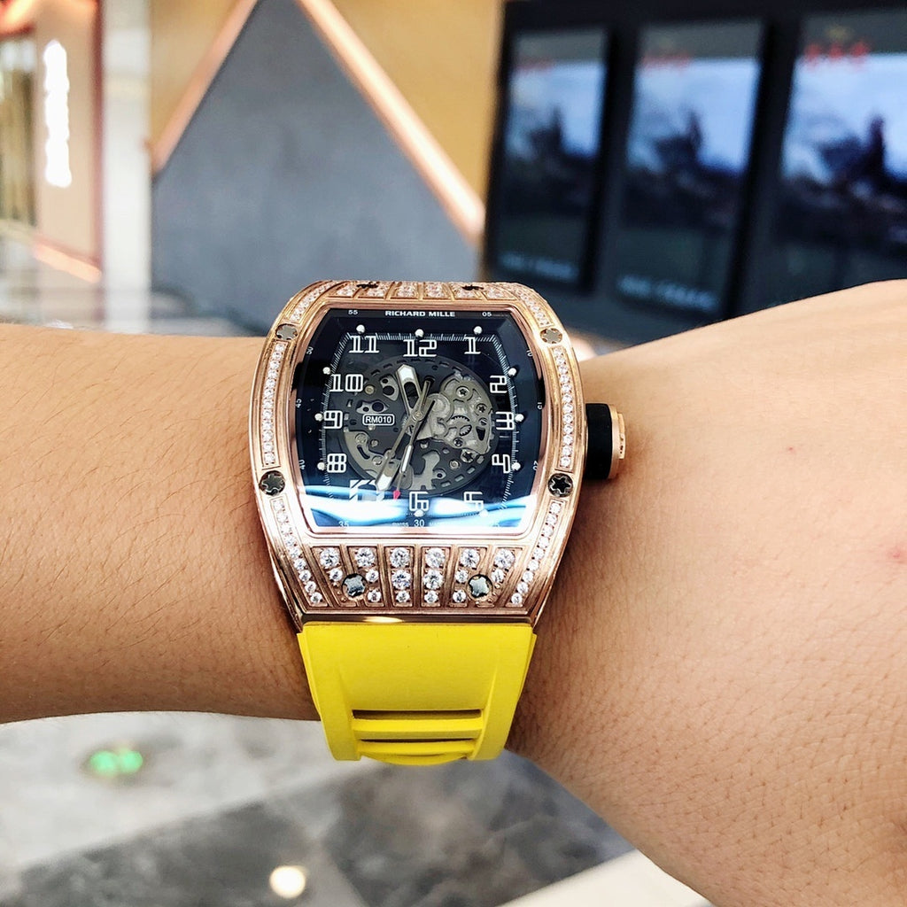 Richard Mille watch on wrist, rose-gold bezel detail, blue dial, yellow silicone strap