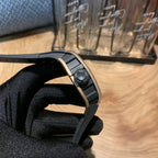 Square watch case side view with black rubber strap and crown detail