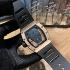 Rose gold-toned square watch with black strap and jeweled bezel, skeleton dial