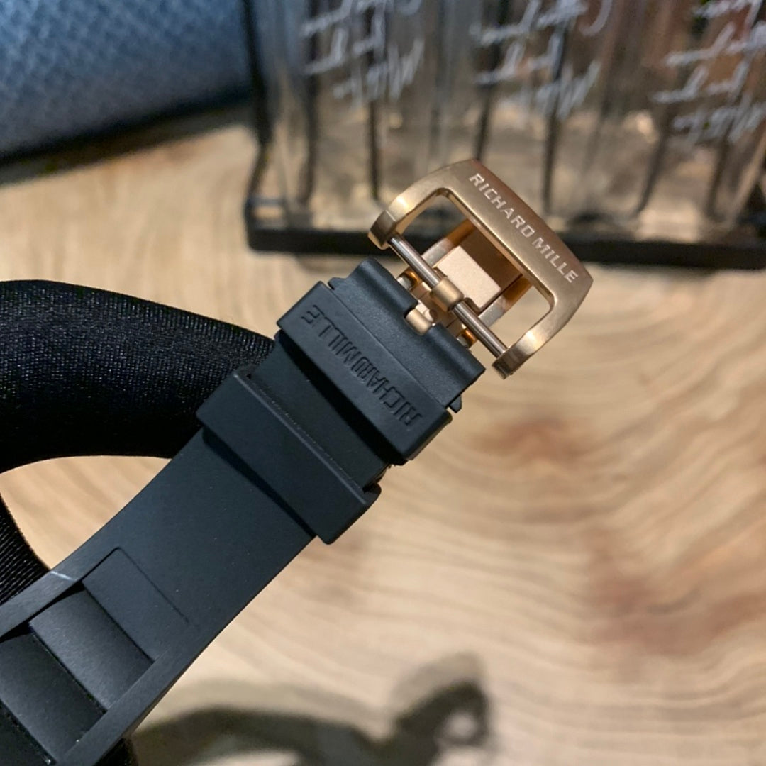 Black rubber watch strap with rose gold-toned metal buckle clasp