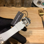 Richard Mille watch on white strap, with black tag and clasp near buckle.