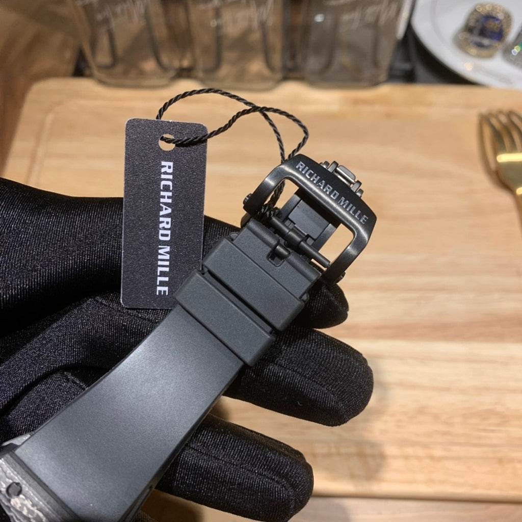 Richard Mille watch accessories view with black strap and clasp plus tag