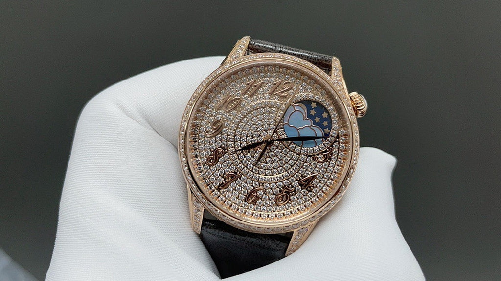 Rose-gold dress watch with diamond bezel, detailed blue moon dial, black leather strap.