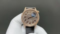 Rose-gold tone dress watch with diamond bezel, black leather strap, blue moon dial.