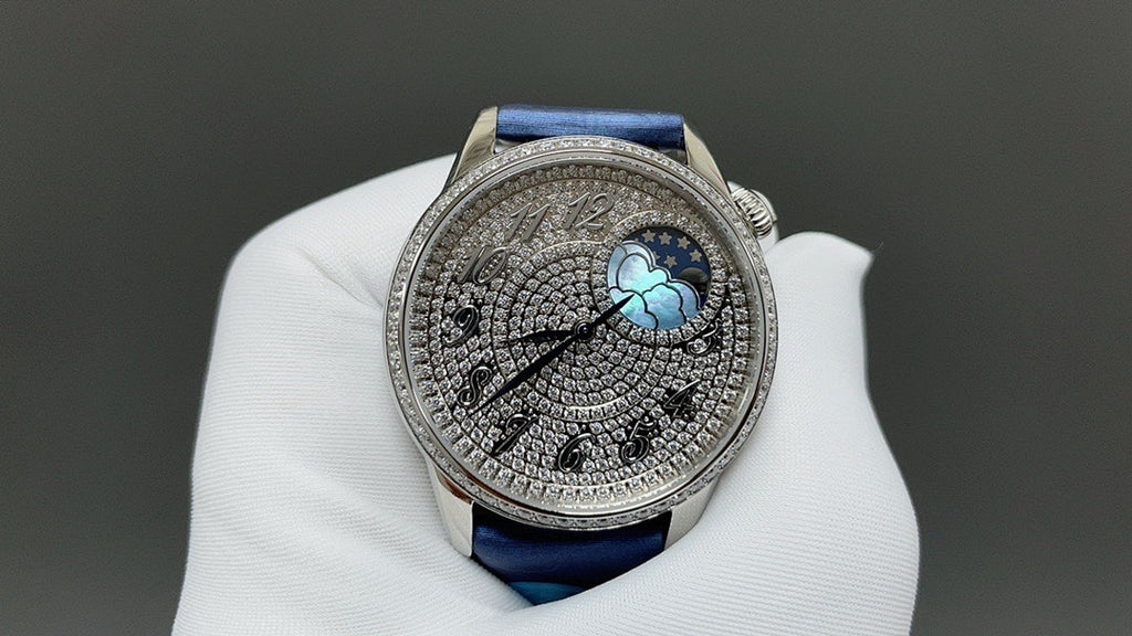 Luxury wristwatch close-up with blue leather strap and patterned silver dial with moon motif