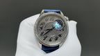 Luxury wristwatch close-up with blue leather strap and patterned silver dial with moon motif