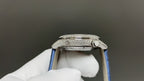 Silver watch case side with blue strap, textured bezel and crown detail