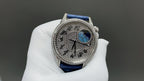 Round watch with silver case and blue leather strap, patterned dial with blue emblem
