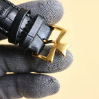 Black leather watch strap with gold-tone deployant clasp and buckle.