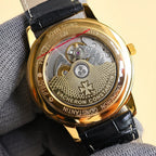 Gold-tone wristwatch case back with engraved movement and black leather strap.
