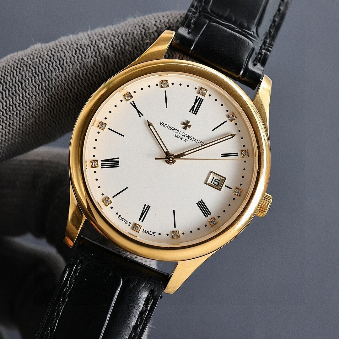 Gold wristwatch with white dial, black leather strap, and date window showing 15