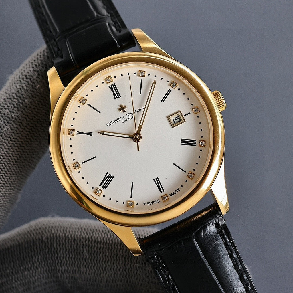Gold wristwatch front at angle with white dial, black leather strap, date window showing 15
