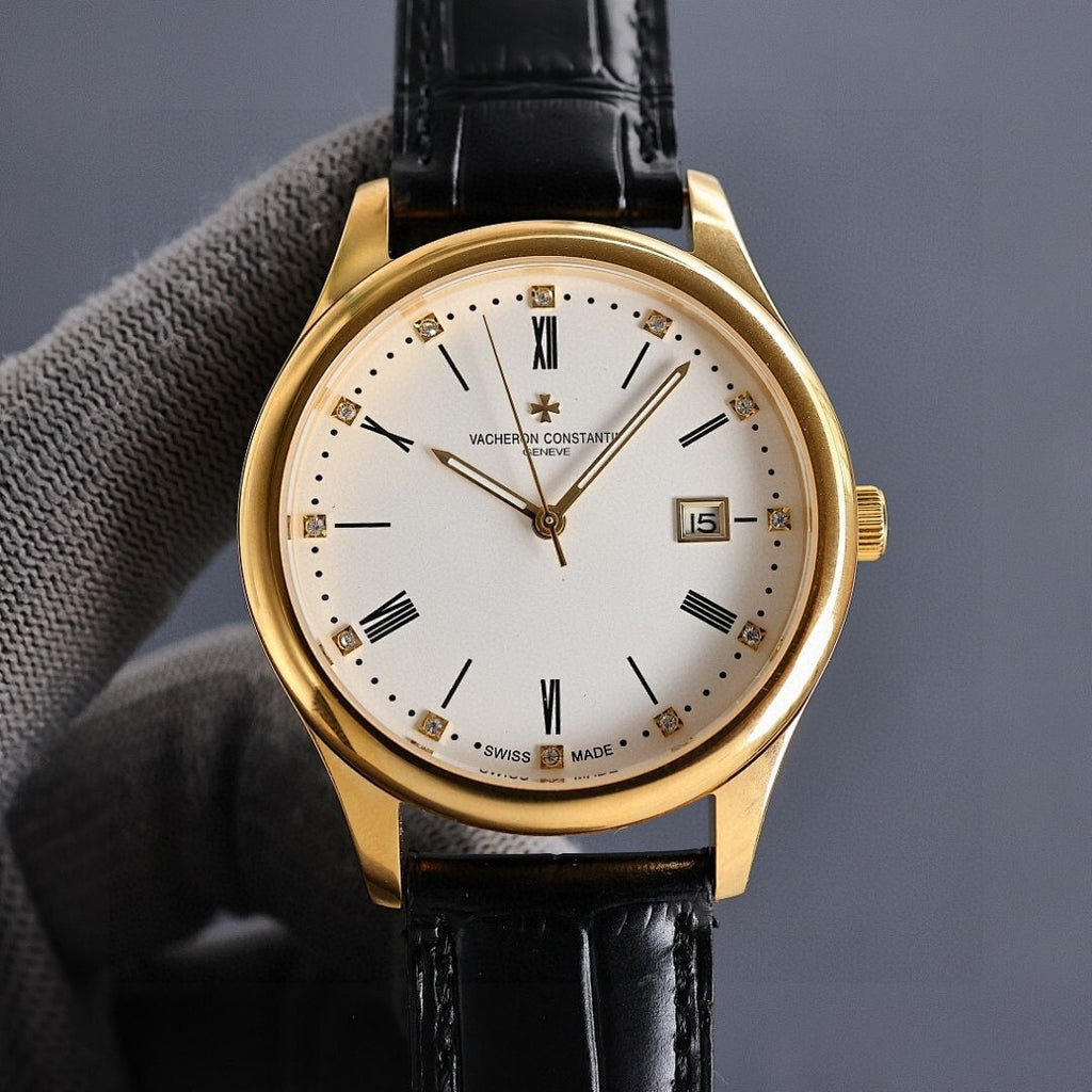 Gold wristwatch with white dial, black leather strap, and date window showing 15