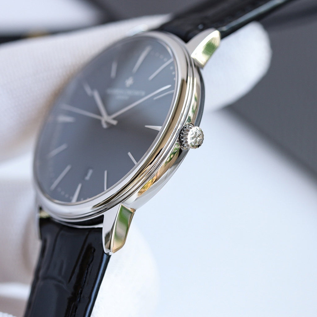Wristwatch side view with crown and black leather strap, steel case