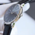 Wristwatch side view with crown and black leather strap, steel case