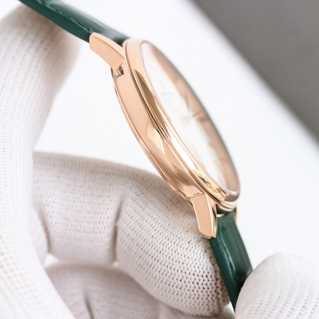 Rose-gold wristwatch with green leather strap and crown, side view on white cushion