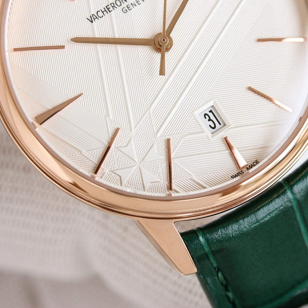 Rose-gold wristwatch with white textured dial, green leather strap, date window near 3