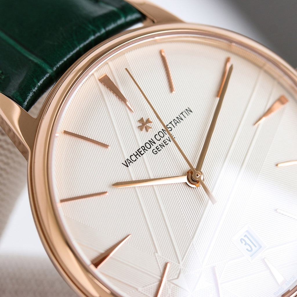 Close-up rose-gold wristwatch with white dial, green leather strap, baton hands and markers