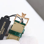 Rose-gold wristwatch case with green leather strap, top view with buckle and tag