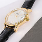 Gold-tone diamond bezel wristwatch with black leather strap, white textured dial and gold hands