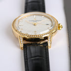Gold-tone diamond bezel wristwatch with black leather strap, white dial with crystal accents