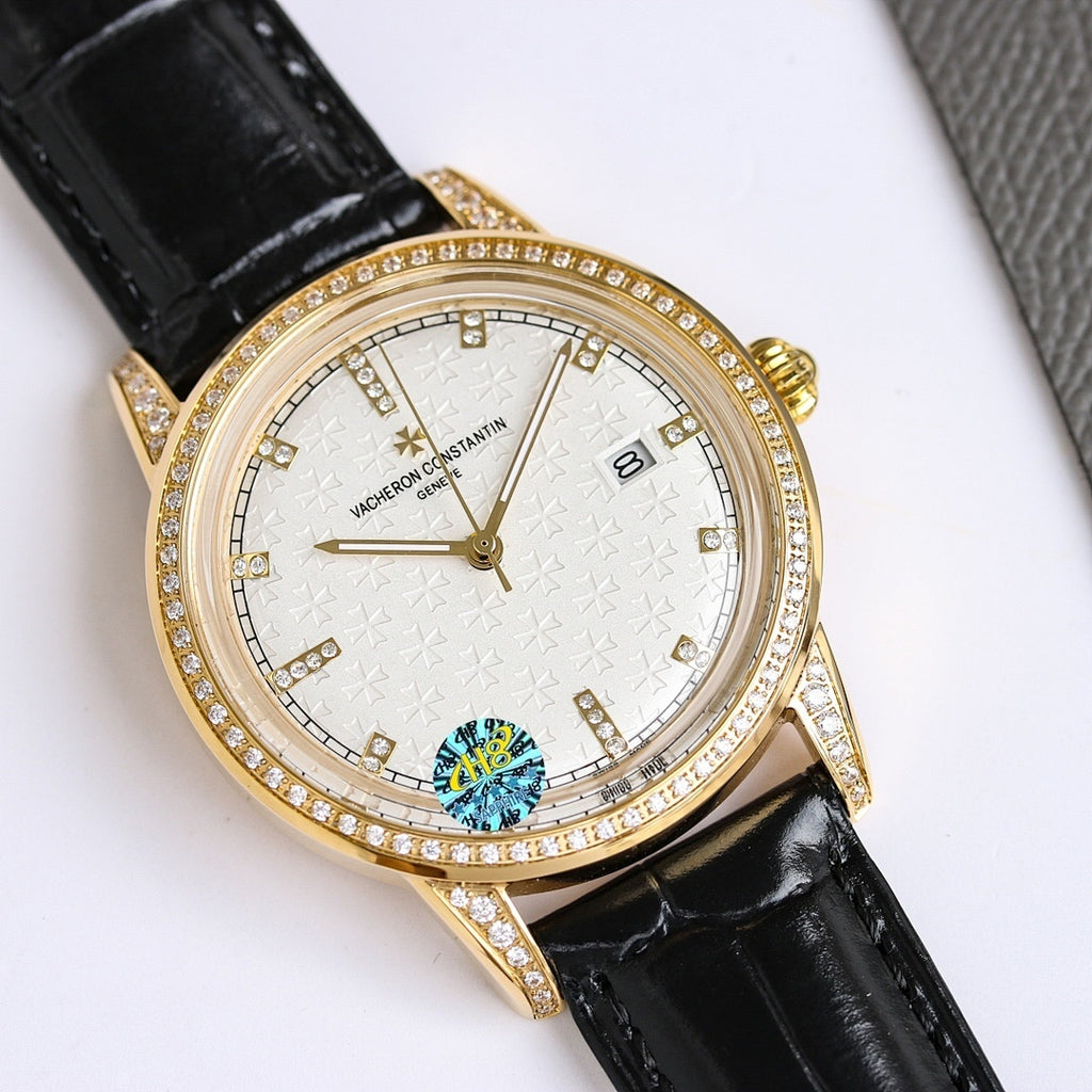 Gold-tone diamond bezel wristwatch with black leather strap, white textured dial and date window