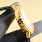 Gold wristwatch case profile with polished bezel and black leather strap