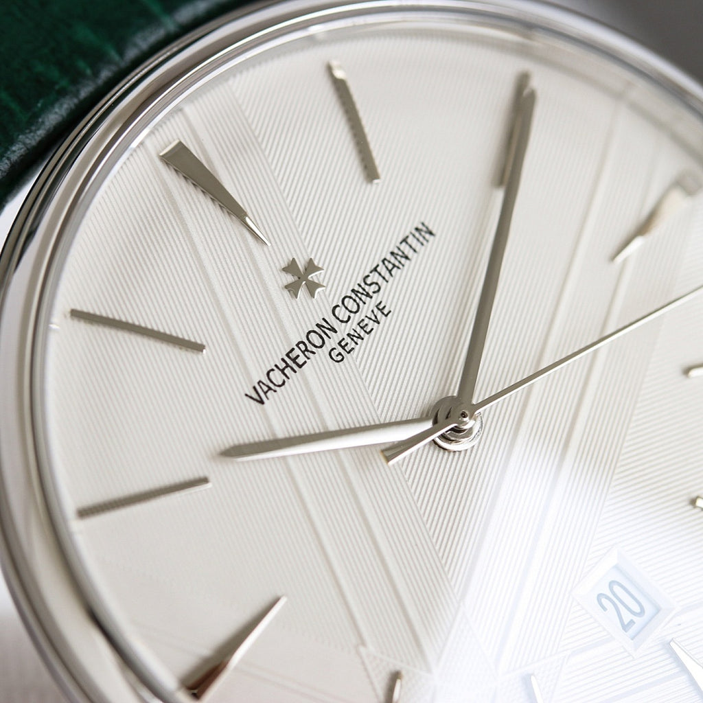 White dial wristwatch with baton markers, star emblem, and green leather strap
