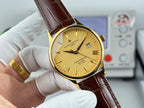 Gold wristwatch with yellow dial and brown leather strap, three-quarter front view