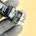 Black leather watch strap with silver buckle hardware and stitched edge