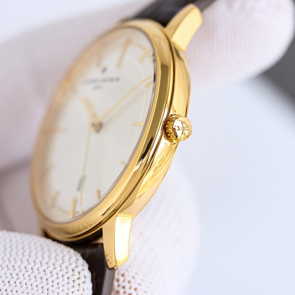 Gold dress watch with white dial and brown leather strap, showing side case and crown