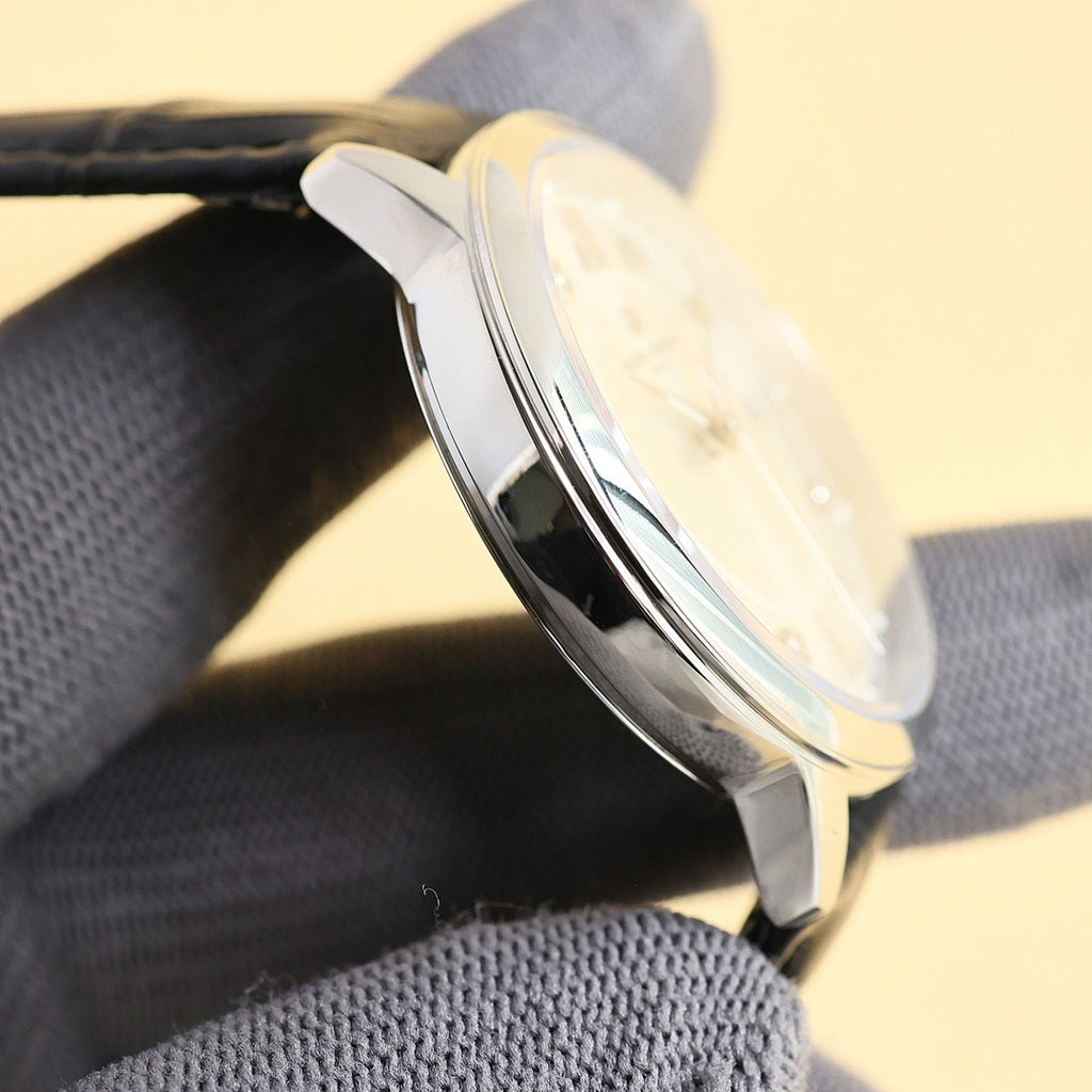 Polished stainless watch case with curved bezel, black leather strap, side view