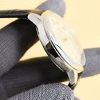 Polished stainless watch case with curved bezel, black leather strap, side view