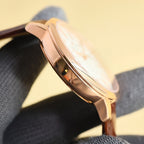Rose-gold watch case side with crown and brown leather strap
