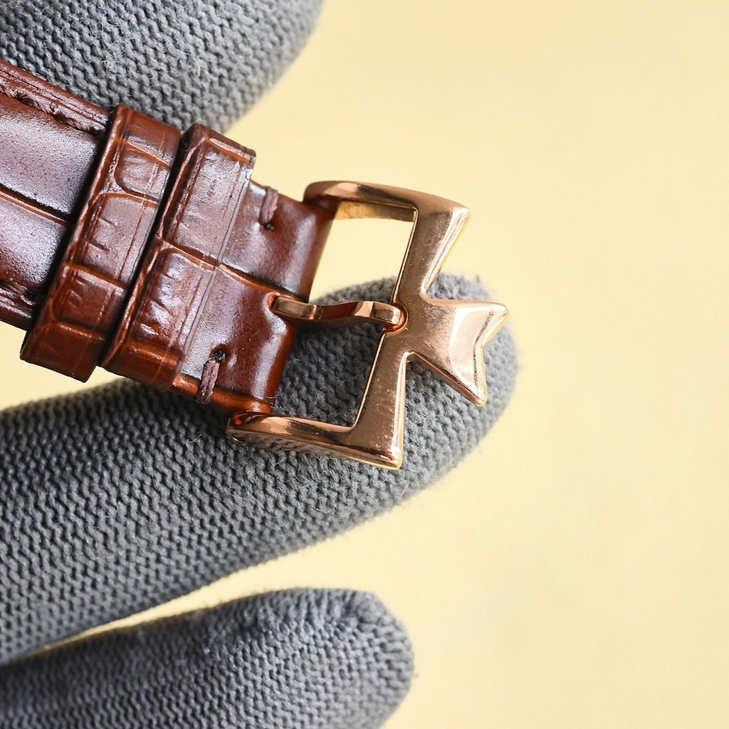 Brown leather watch strap with gold clasp buckle and star-shaped keeper