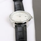 Silver luxury wristwatch with white dial, diamond bezel, black leather strap