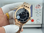 Gold-tone wristwatch with black dial and metal bracelet, held in gloved hands