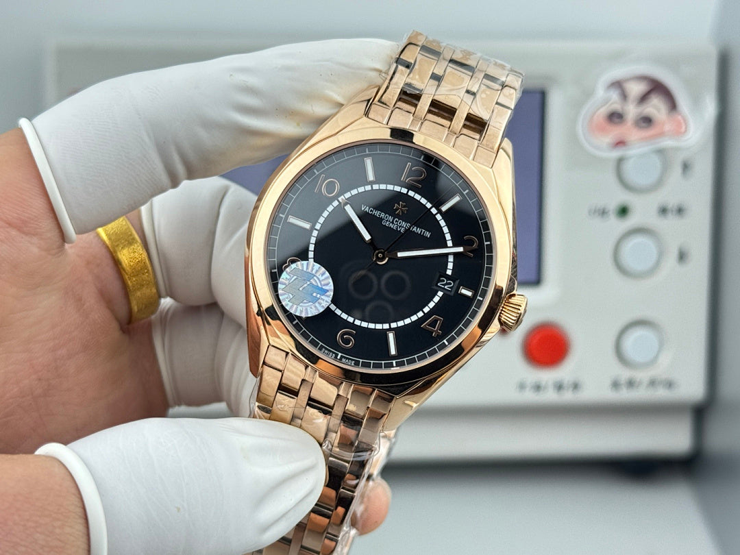Gold-tone wristwatch with black dial and metal bracelet, held in gloved hands