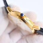 Gold watch case side with blue gemstone crown, black leather strap