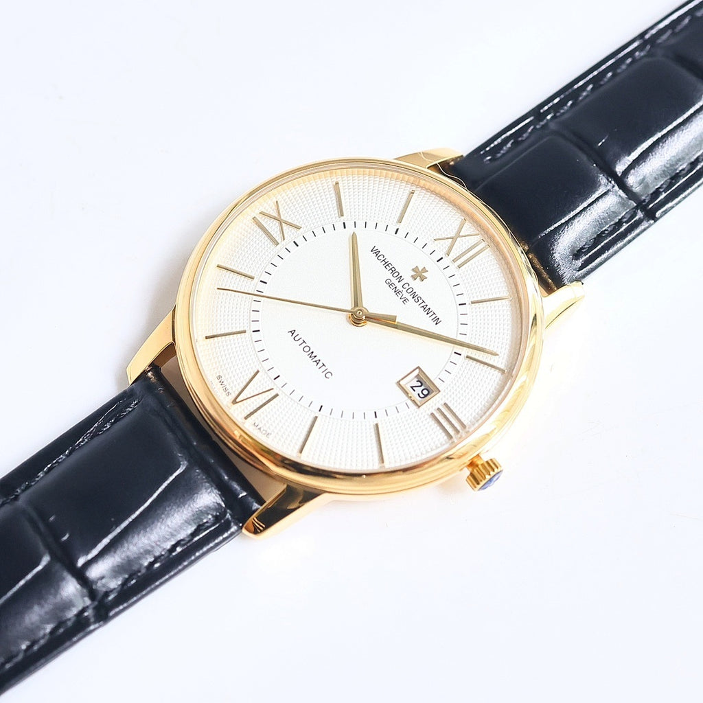Automatic wristwatch with white textured dial, Roman numerals, date window, gold case, black strap